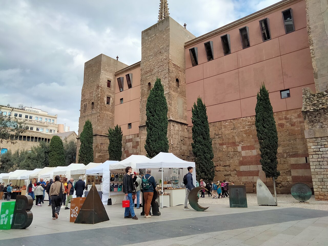 Roman wall towers on Plaça Nova in Barcelona's Gothic Quarter, with letter sculptures in the square